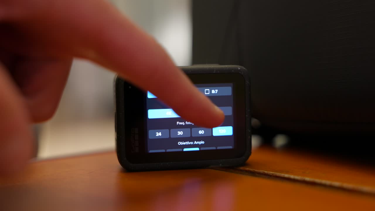 Close Up Hand Touching Back Screen Of Action Camera Resting On Table Indoors