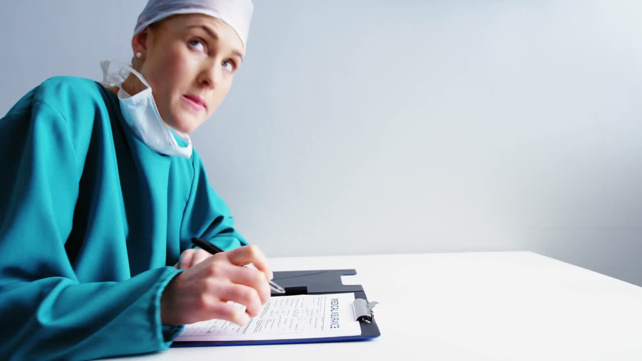 Vrouwelijke arts die op een klembord schrijft