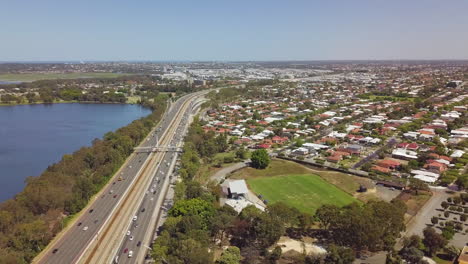 aéreo, autopista concurrida entre el suburbio residencial y el lago, perth, australia