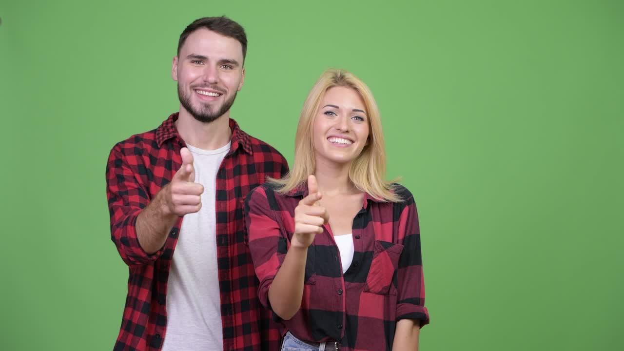 Young happy couple pointing to camera together