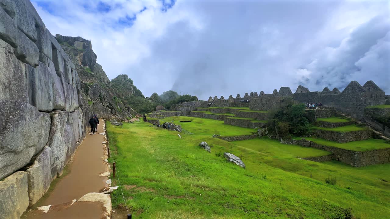 Circuito turistico di Machu Picchu cielo azzurro soleggiato nuvole mattina Perù Perú monte Huayna Picchu stagione delle piogge verde lussureggiante Ande peruviane Tempio Inca Santuario giungla lavoro in pietra terrazza static shot