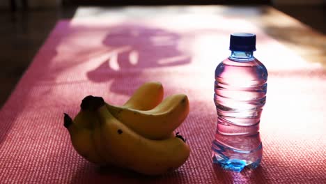 banana and water bottle on exercise mat at home 4k