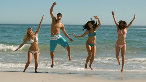 jóvenes alegres saltando en la playa