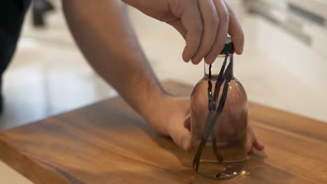 Man-closes-glass-bottle-with-vanilla-beans-and-vodka-to-make-homemade-vanilla