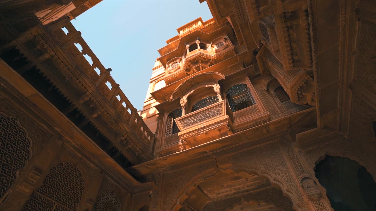 Toma estática cinematográfica en ángulo contrapicado del patio interior y los balcones de arenisca ornamentados en Patwon Ki Haveli en Jaisalmer, Rajastán, India