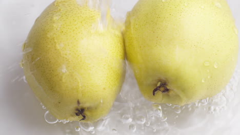 Yellow-pear-on-a-blue-dark-background-with-drops-of-water-rolling-down-the-pear-and-flowing-splashing-with-isolated-background