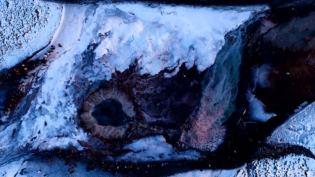 maravillosa vista aérea sobre un geyser en geysir, islandia. el humo está saliendo del geyser con la gente caminando alrededor del geyser, bajo la puesta de sol.