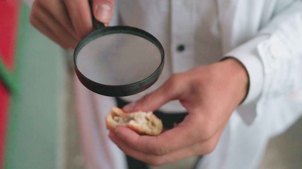 Close up view of botany student in white coat carefully examining pastry through magnifying glass during outdoor research, reflecting focus, curiosity, and dedication to scientific observation