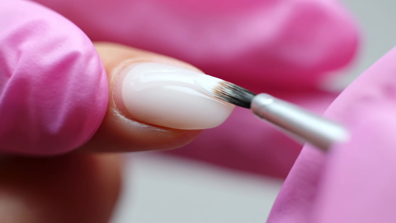 Closeup Nail Polish Application With Pink Gloves. Manicurist Uses Small Brush To Apply Opaque White Gel