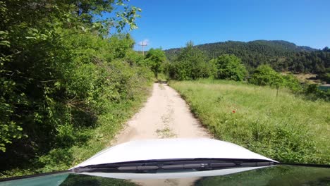 Car-driving-on-a-dirt-road-alongside-of-a-lake