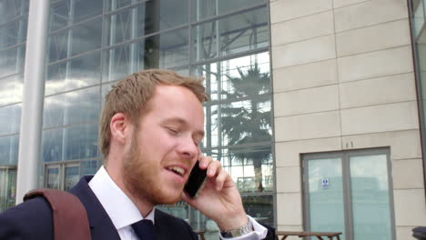 Young-man-walking-to-entrance-of-a-modern-business-building