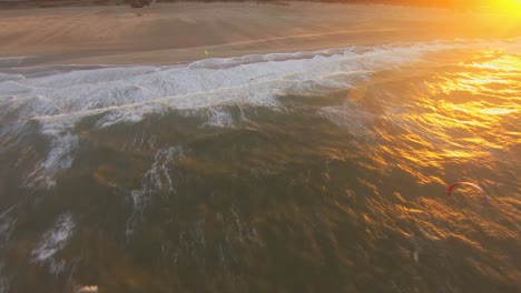 Toma-Aérea-Cercana-De-Un-Kitesurfer-Saltando-Durante-La-Puesta-De-Sol