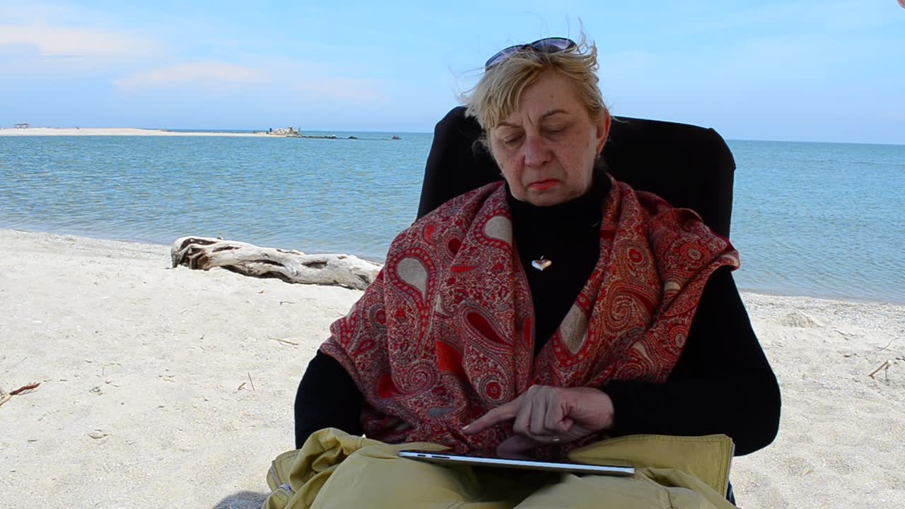 Il tablet nelle mani della signora. Scatto dell'anziana al mare