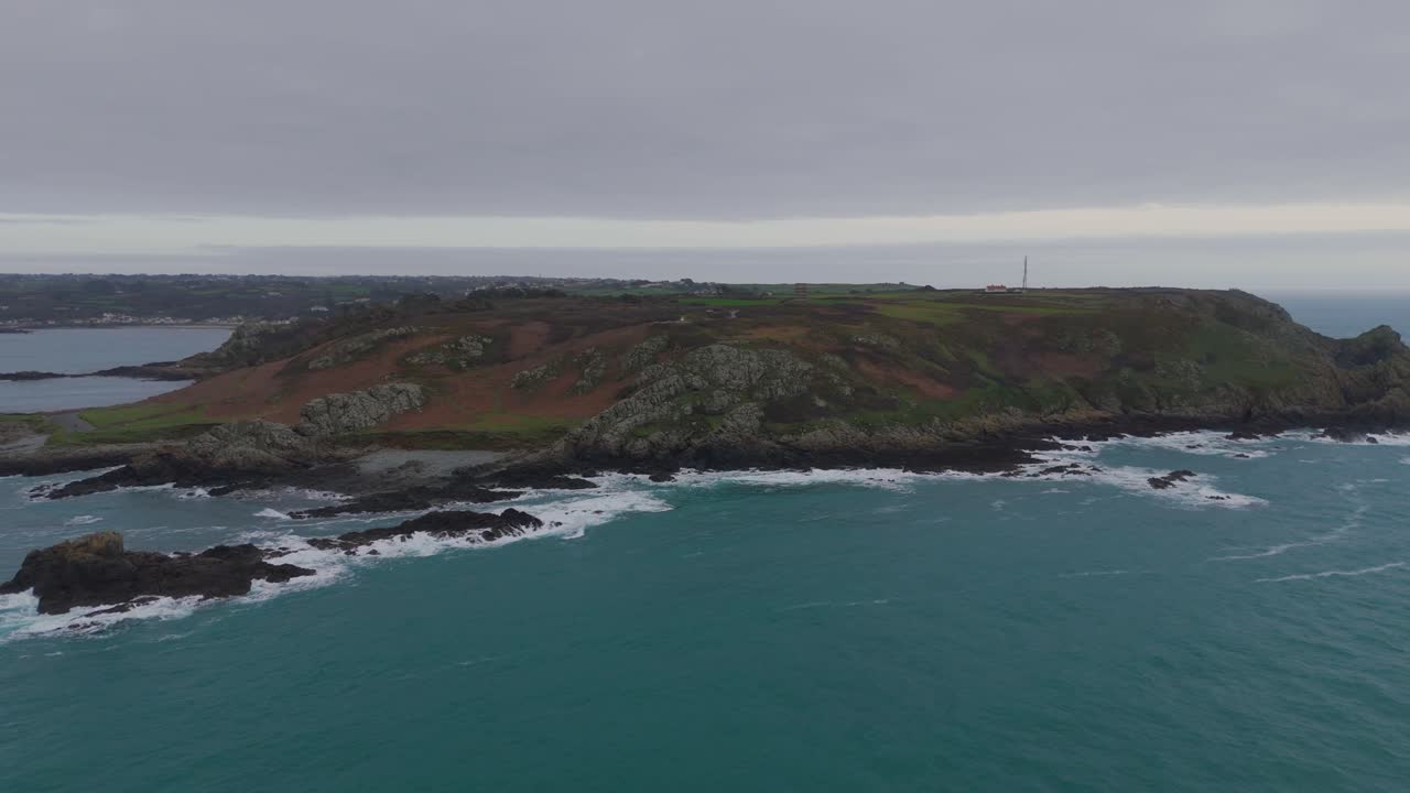 guernsey pleinmont, vuelo desde el mar hacia el extremo suroeste de la isla en un día nublado mostrando acantilados, playas y rocas y la torre de comunicaciones de la bbc