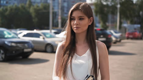 Attractive-woman-in-white-blouse-walks-along-parking-area