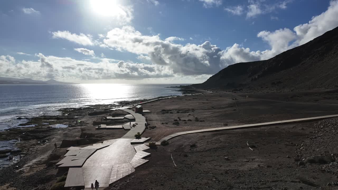 엘 콘피탈 해변의 시간 경과, 푸른 하늘에서 빛나는 태양과 함께 화산 풍경, 약간의 구름과 사람들이 고 있습니다.