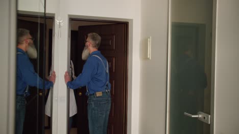 a happy middle-aged man with raw hair and a lush beard in glasses and a blue shirt meets a female doctor in a white coat and with a doctor on the threshold of his house