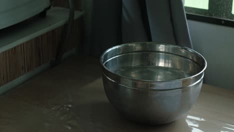 placing hard-boiled eggs with tongs into a steel bowl of cold water to cool down. -static shot