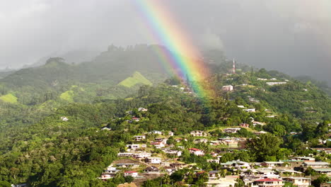 drone shot of real rainbow above hills of tahiti island and papeete city, french polynesia