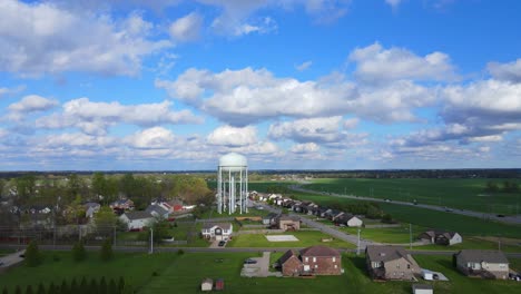 volando hacia una torre de agua en un barrio suburbano en un día nublado con cielos azules 4k