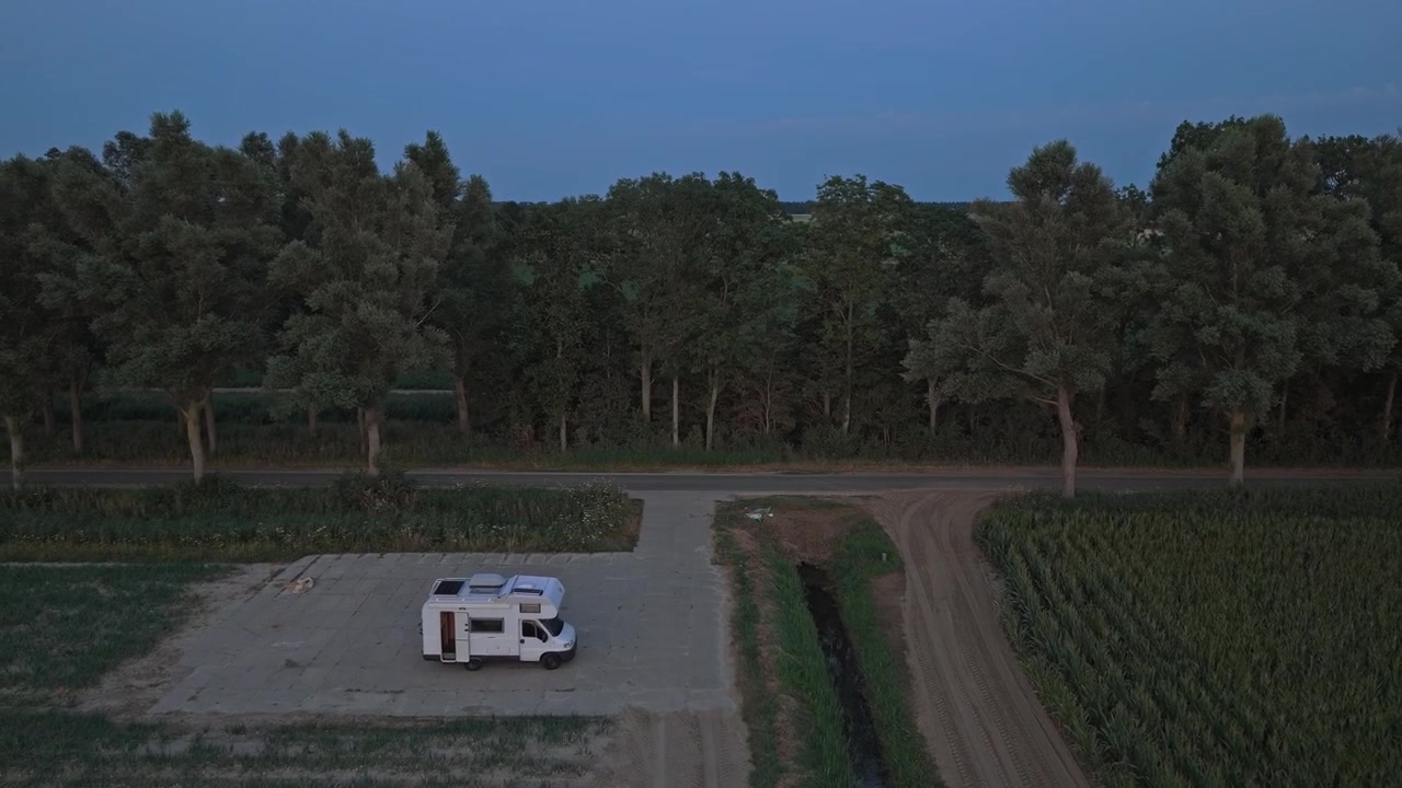 Vista aerea di un camper parcheggiato in un campo rurale al crepuscolo