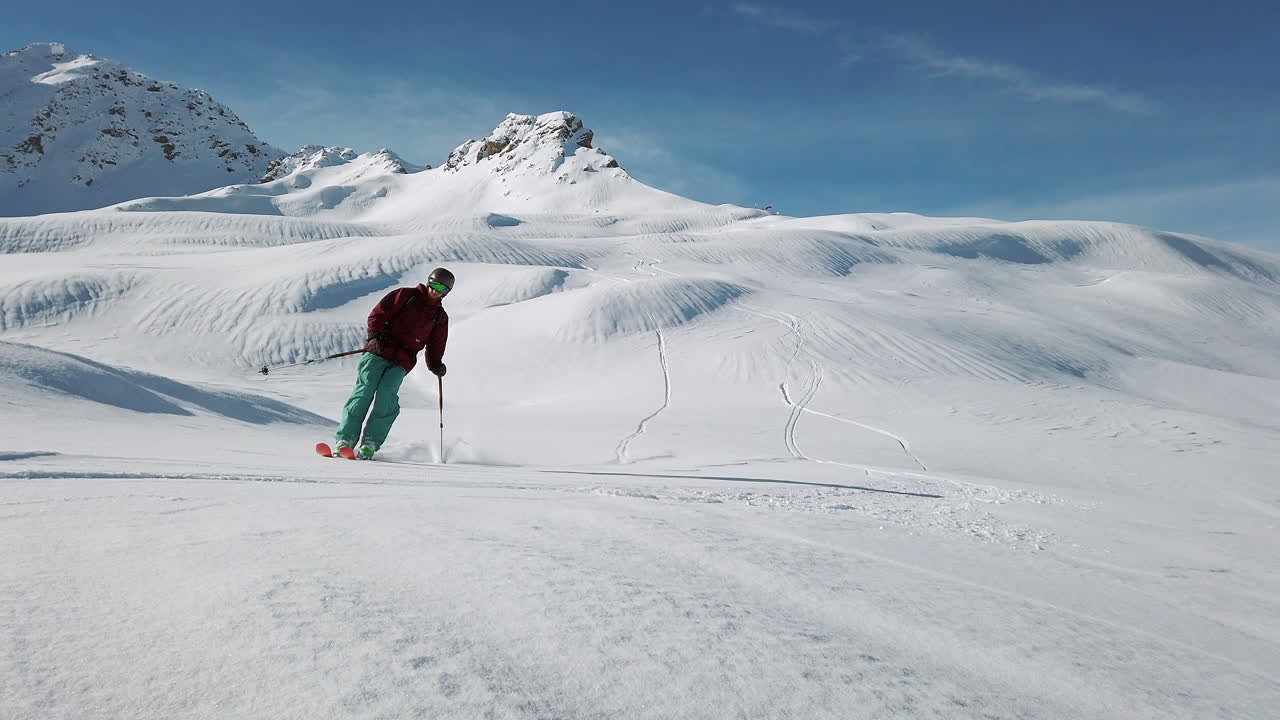 Uno sciatore solitario esegue una frenata in derapata sollevando neve fresca e polverosa, catena del Montafon, Alpi austriache, al rallentatore