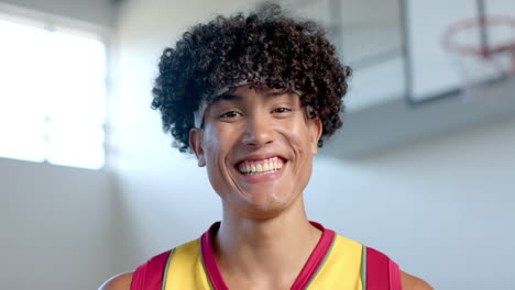 Un-Joven-Birracial-Con-Pelo-Rizado-Sonríe-Alegremente-En-Una-Cancha-De-Baloncesto