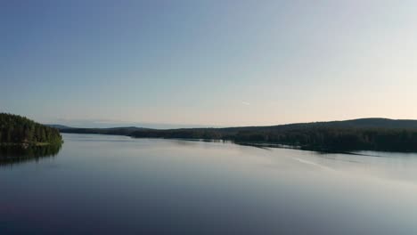 calm lake with forested shores and clear sky reflection