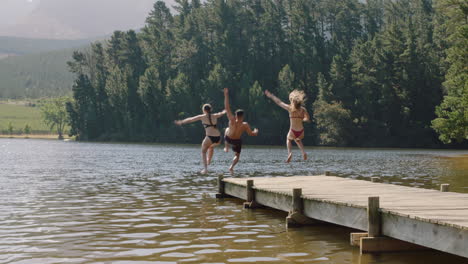 Glückliche-Freunde,-Die-Vom-Steg-Im-See-Springen,-Im-Wasser-Planschen-Und-Die-Freiheit-Genießen-Und-Im-Urlaub-Ein-Lustiges-Sommerabenteuer-Erleben