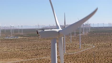aerial view rising above numerous wind turbines scattered across the vast mojave desert, california