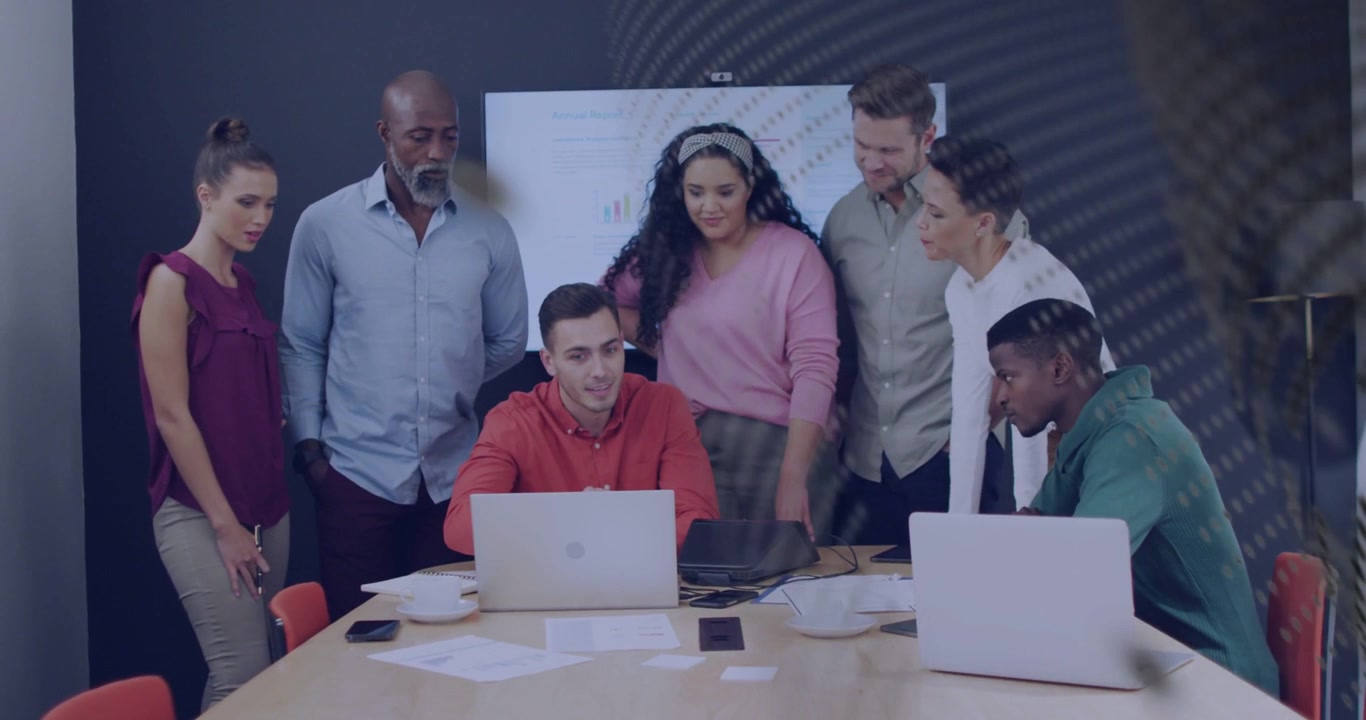 Team læner sig over laptops, leder ved laptop forårsager gitter-overlay, der skjuler diagrammer til forretningsgennemgang