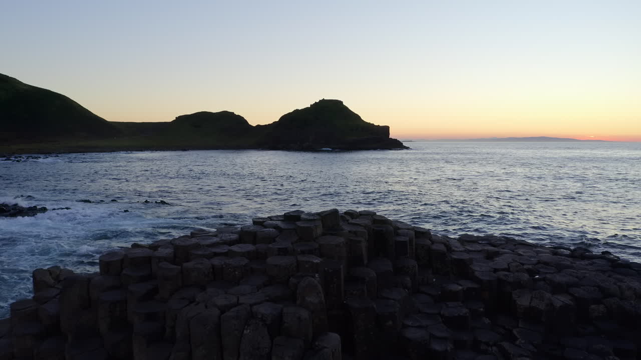 Aerial dolly over the hexagonal basalt formations of Giant's Causeway at sunset