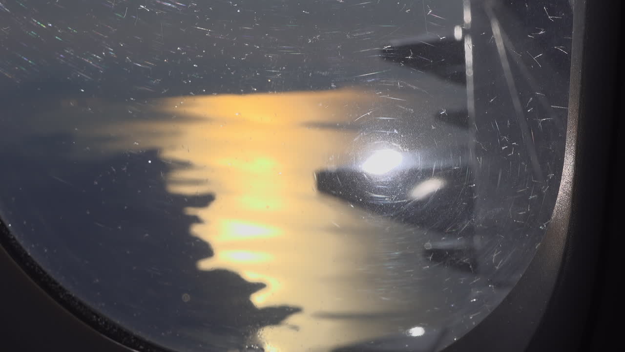 View from an airplane window of the sunset reflecting on the sea