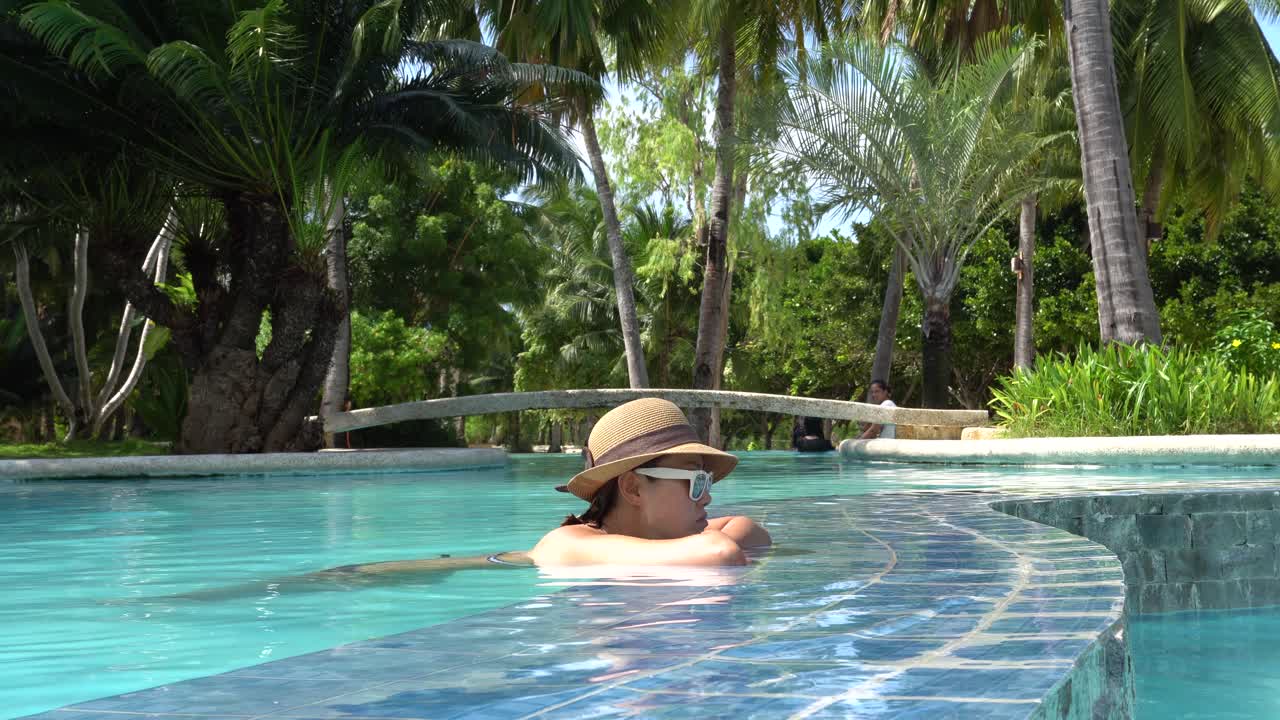 Uma mulher deslumbrante relaxando na piscina do Dos Palmas Island Resort em Puerto Princesa, Palawan, Filipinas - Tomada de baixo ângulo