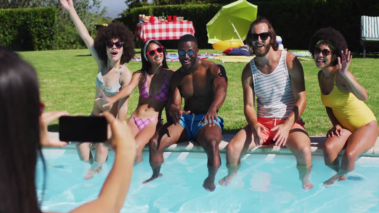 grupo de diversos amigos posando para una foto mientras están sentados junto a la piscina