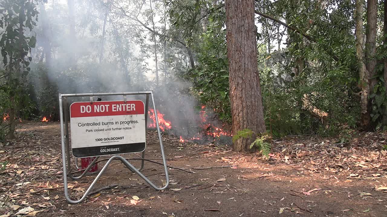 Controlled burn on Queensland's Gold Coast. Sign with fire in background.