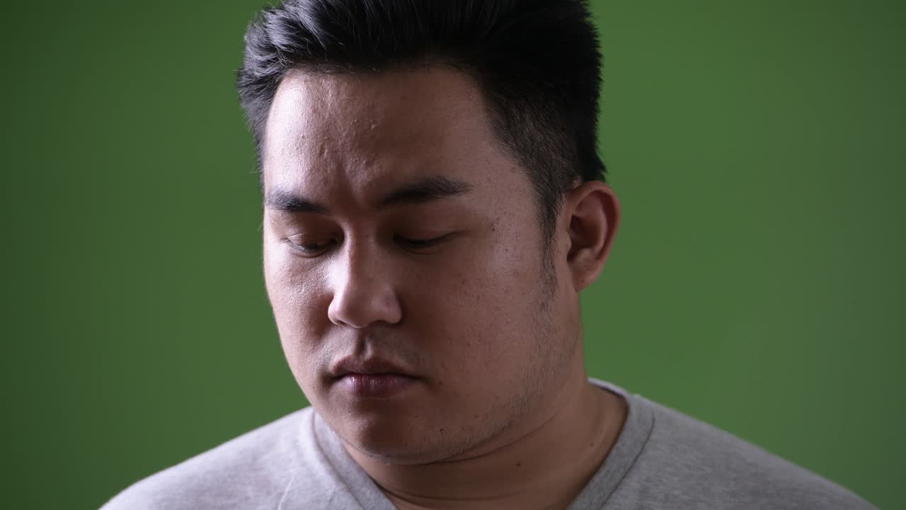 초록색 배경에 젊은 잘생긴 과체중 아시아인