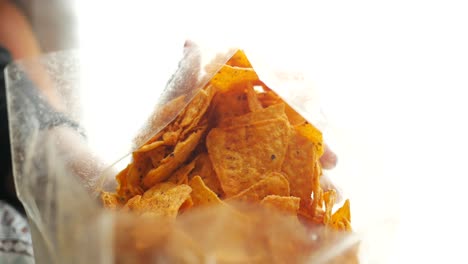 una mano alcanzando una bolsa de papas fritas de tortilla