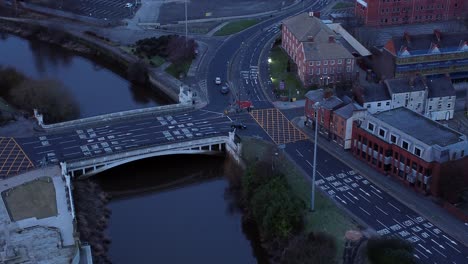 aerial view looking down city centre canal roundabout infrastructure suburban streets traffic at daybreak slow orbit left