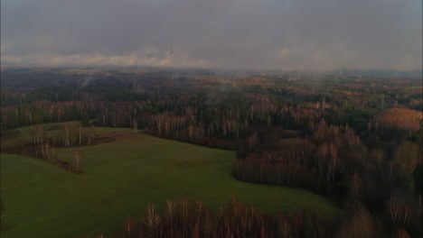 mist floating above the treeline in wooded countryside and lush green pastures