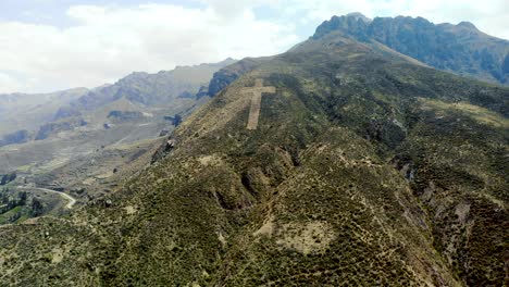 Toma-Aérea-Hacia-Atrás-De-Un-Enorme-Crucifijo-Católico-Hecho-A-Mano-En-La-Ladera-De-La-Montaña-En-Chivay-Perú