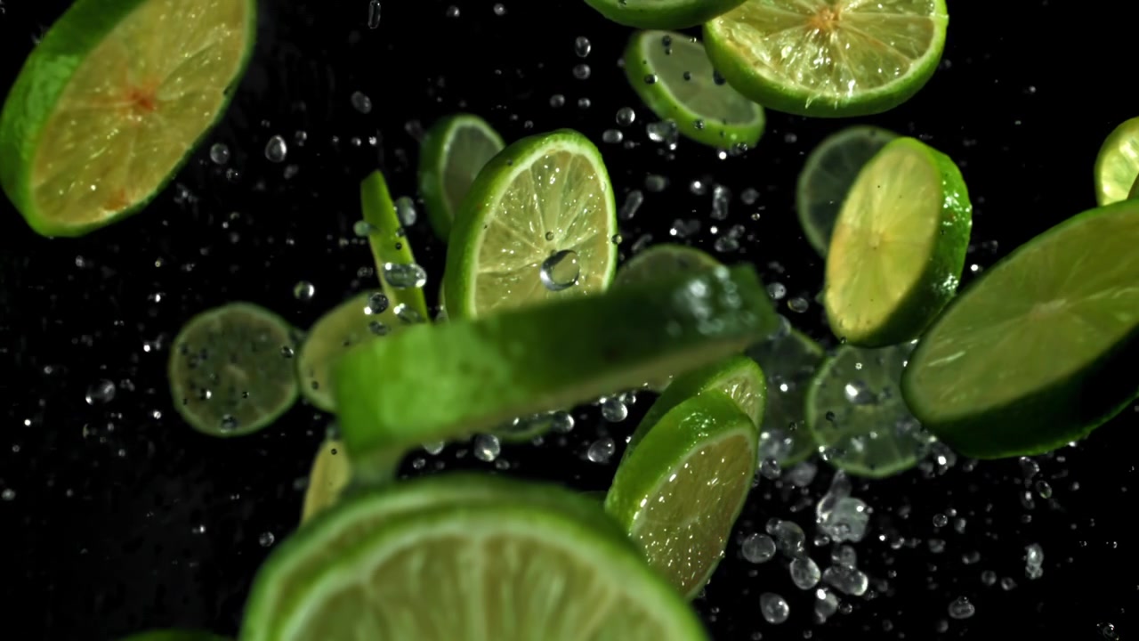 Fette di lime fresco che cadono con schizzi d'acqua su sfondo nero
