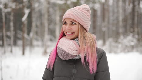 woman in a jacket and hat in slow motion looks at the snow and catches snowflakes smiling