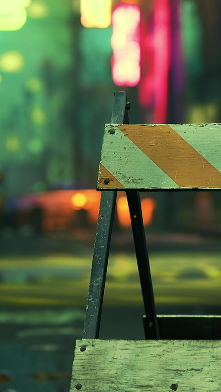 City lights reflect off a construction barrier in a quiet urban street
