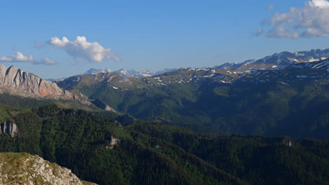 Panoramic-landscape-view-of-the-rocky-Caucasus-Mountains-with-valleys-and-forests-from-above,-on-a-sunny-day