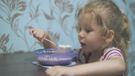 cute girl eats tasty pasta with milk at table in light room