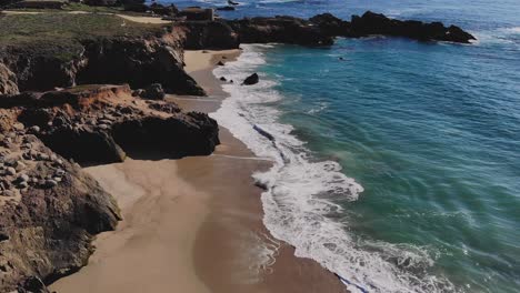 Waves-crashing-on-sunny-rocky-coastal-beach-during-late-afternoon