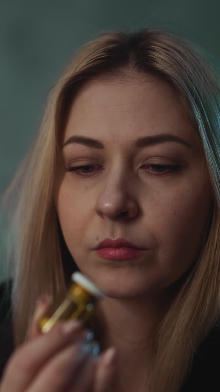 una mujer rubia mira un frasco de pastillas de vidrio con aditivos biológicamente activos dudando de la receta del médico en una habitación semi-oscura de vista cercana extrema en cámara lenta