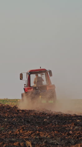 tractor working on large field. farmer in tractor preparing land with seedbed cultivator vertical video