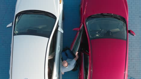 young handicapped driver getting in red car from wheelchair